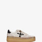 A low-top platform sneaker by Premiata, featuring a cream and beige suede and mesh upper, a black cross logo on the side, gold-tone hardware, and a thick tan gum sole.